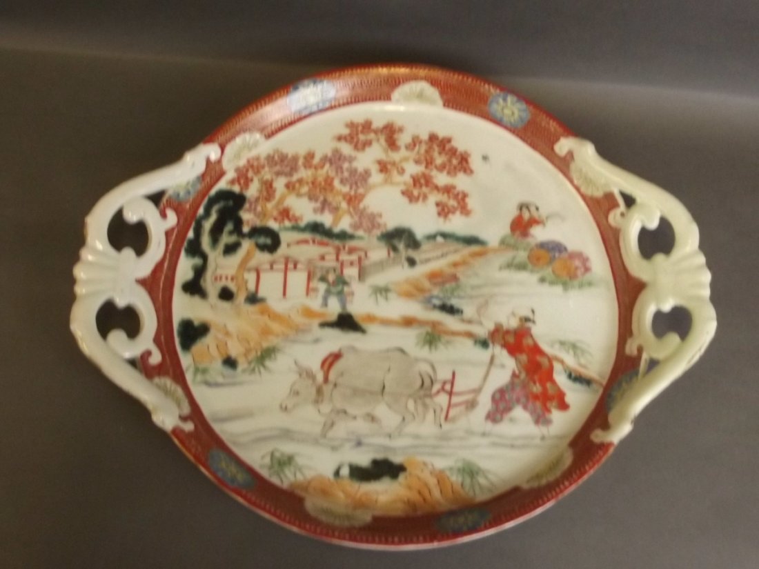 A large Japanese charger decorated with a farmer: A large Japanese charger decorated with a farmer ploughing amongst trees and buildings, with twin handles, 13'' diameter