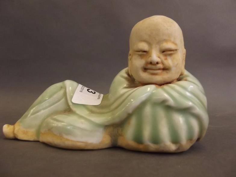 A celadon glazed stoneware figure of Buddha reclining,: A celadon glazed stoneware figure of Buddha reclining, 6" long (AF)