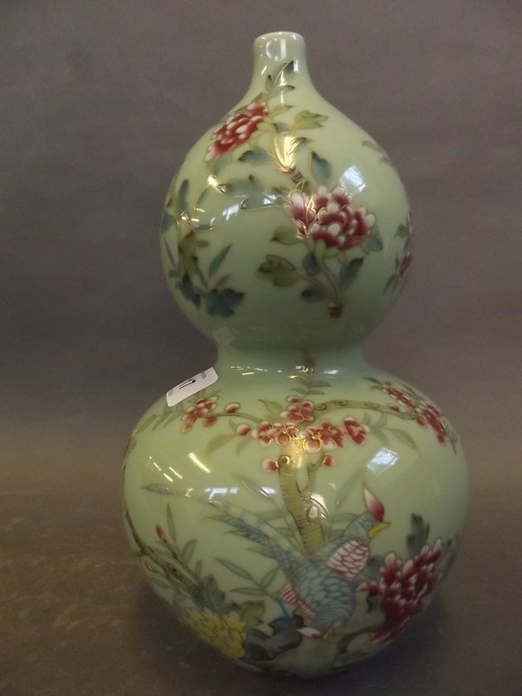 A Chinese porcelain double gourd vase decorated with: A Chinese porcelain double gourd vase decorated with exotic birds in a flowering tree on a pale green ground, blue seal mark to base, 9Â½" high