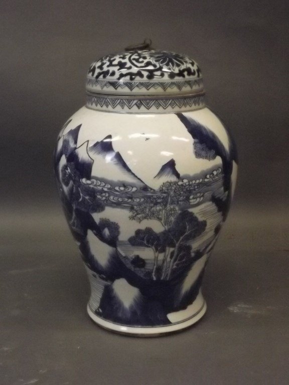 A Chinese porcelain jar and cover decorated with: A Chinese porcelain jar and cover decorated with landscapes in the blue and white palette, the lid with stylised lotus, 13" high (AF hairline crack to base)
