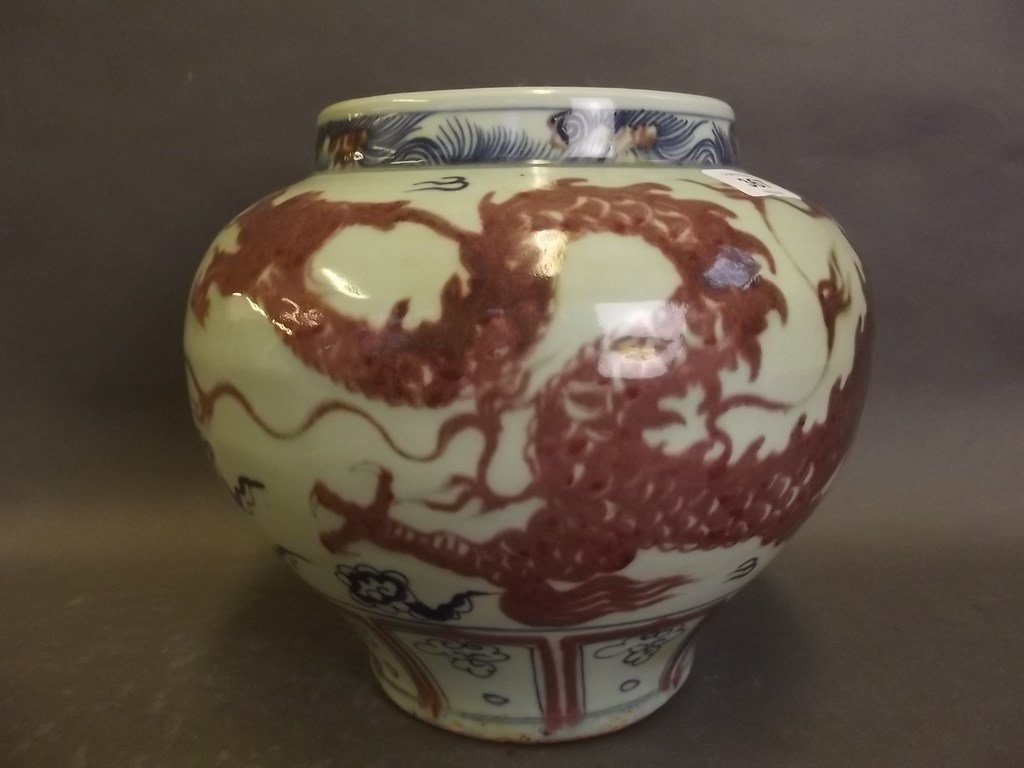 A Chinese blue and white porcelain jardiniÃ¨re of: A Chinese blue and white porcelain jardiniÃ¨re of bulbous form, decorated with an ironstone red dragon amongst blue clouds, 9Â½" high