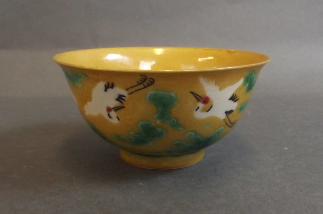 A Chinese yellow ground tea bowl with incised and: A Chinese yellow ground tea bowl with incised and enamelled stork decoration, 6 character mark to base, 4" diameter