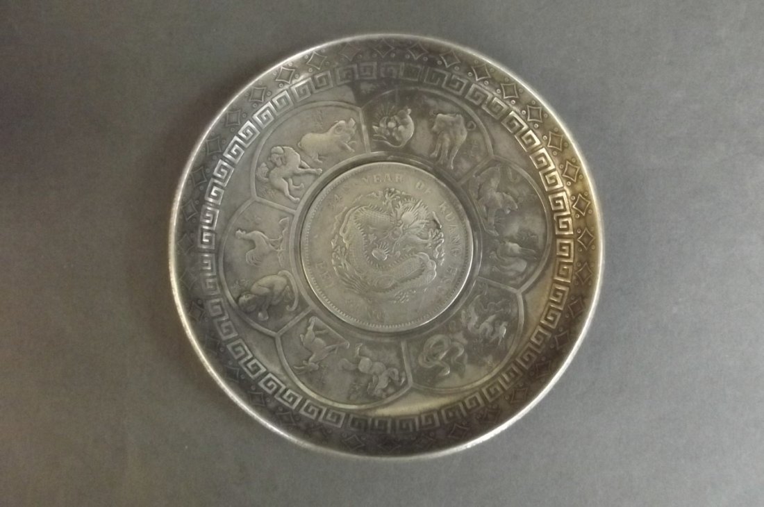 A Chinese white metal dish decorated with zodiac: A Chinese white metal dish decorated with zodiac animals around a central coin, 3" diameter