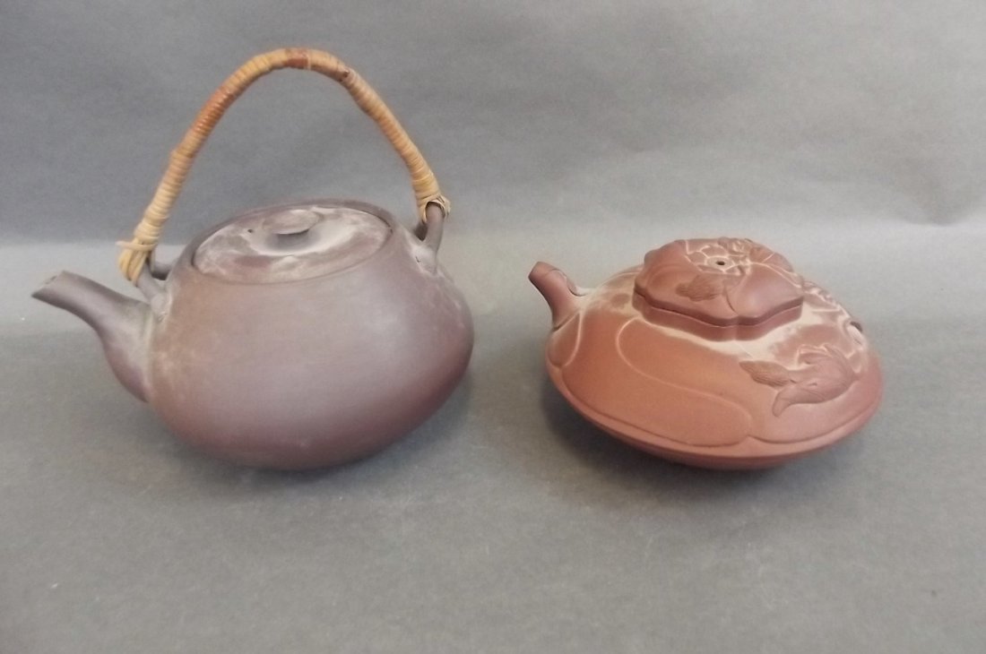 A Chinese Yixing teapot of compressed form with: A Chinese Yixing teapot of compressed form with embossed leaf decoration, together with a Chinese red earthenware teapot with bamboo handle, 6" high (AF)