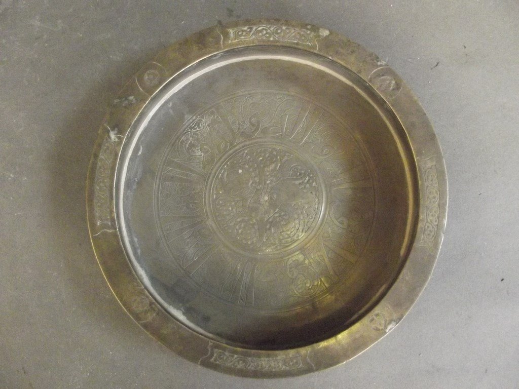 A Persian bronze bowl with engraved decoration of: A Persian bronze bowl with engraved decoration of Islamic calligraphy around a central design of a Harpy, 7" diameter