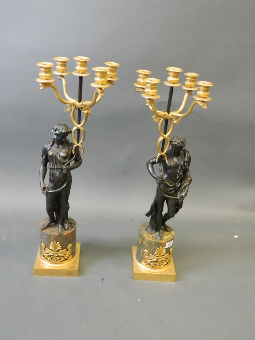 A pair of bronze and ormolu mounted five branch: A pair of bronze and ormolu mounted five branch candelabra in the form of classical figures holding caduceus, on marble bases, 27" high