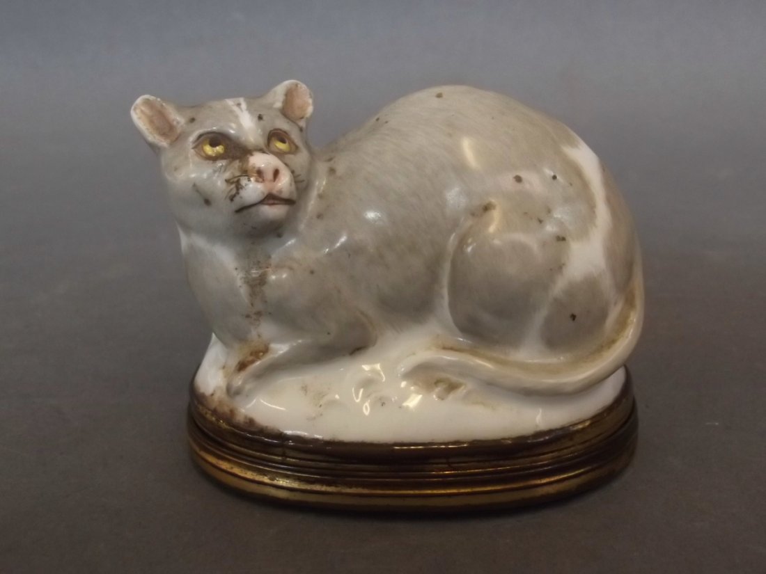 A Continental porcelain bonbonniere in the form of a: A Continental porcelain bonbonniere in the form of a crouching cat with gilt interior, the gilt metal mounted lid with Mother of Pearl and etched flower decoration, probably early C19th, 2½" long