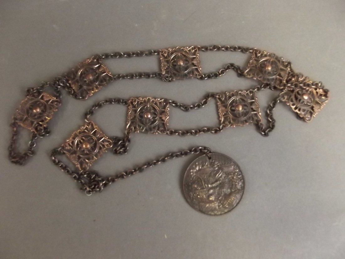 A pierced bronze panel and chain link belt with bronze: A pierced bronze panel and chain link belt with bronze flower seller medallion, 35" long, Best Bid
