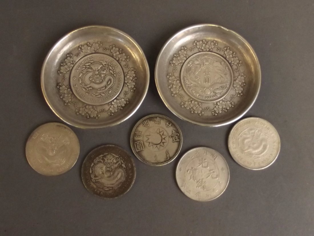 A pair of Chinese silvered metal coin dishes with: A pair of Chinese silvered metal coin dishes with fruiting vine decoration, together with five coins, dish 3" diameter