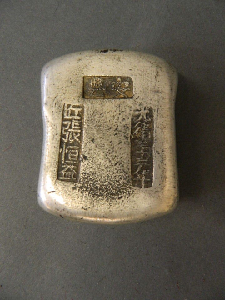 A Chinese white metal trade ingot, impressed character: A Chinese white metal trade ingot, impressed character marks, 2½" x 2"