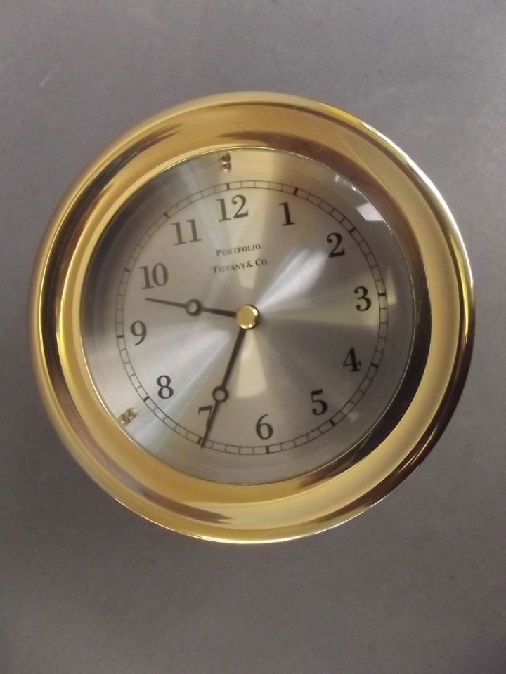 A brass cased portfolio bulkhead clock with quartz: A brass cased portfolio bulkhead clock with quartz movement by Tiffany & Co., 5" diameter