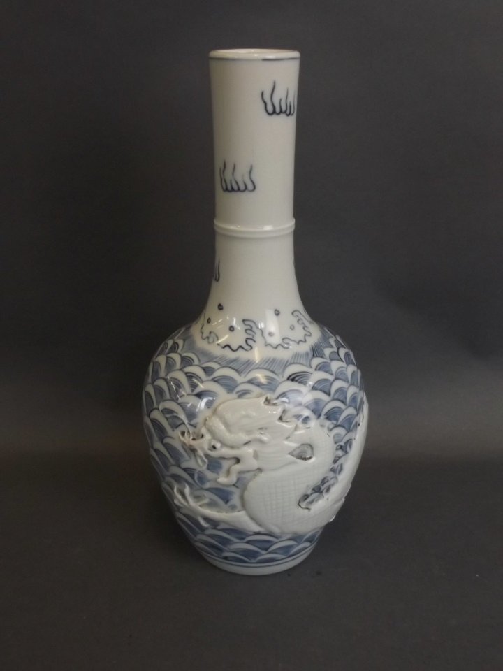A Chinese porcelain bottle vase with relief dragon and: A Chinese porcelain bottle vase with relief dragon and flaming pearl decoration, impressed seal mark to base, 9" high
