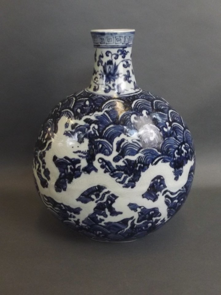 A Chinese blue and white porcelain moon flask with: A Chinese blue and white porcelain moon flask with incised dragon decoration, impressed mark to base, 11" high