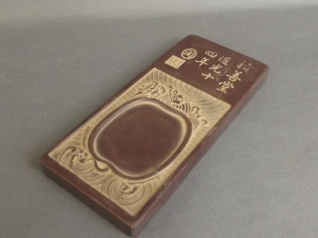 A Chinese brown soapstone ink stone with carved: A Chinese brown soapstone ink stone with carved character decoration to sides, 4" x 9"