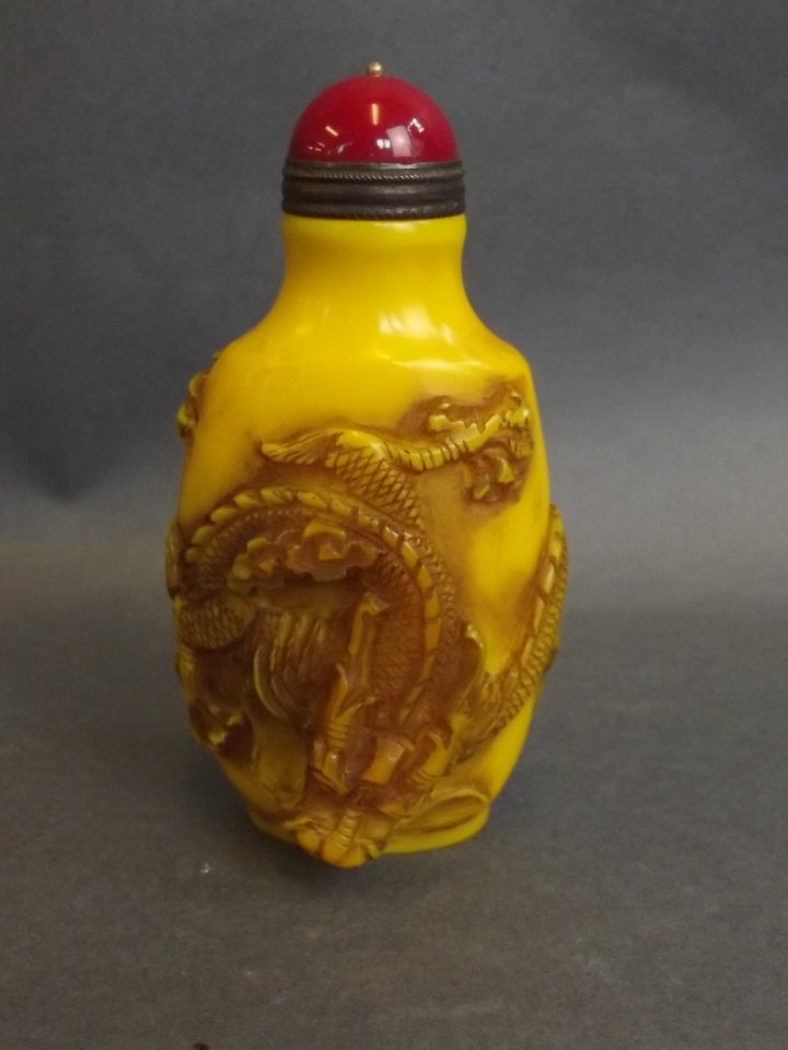 A Peking glass snuff bottle with carved and raised: A Peking glass snuff bottle with carved and raised dragon decoration, 3" high