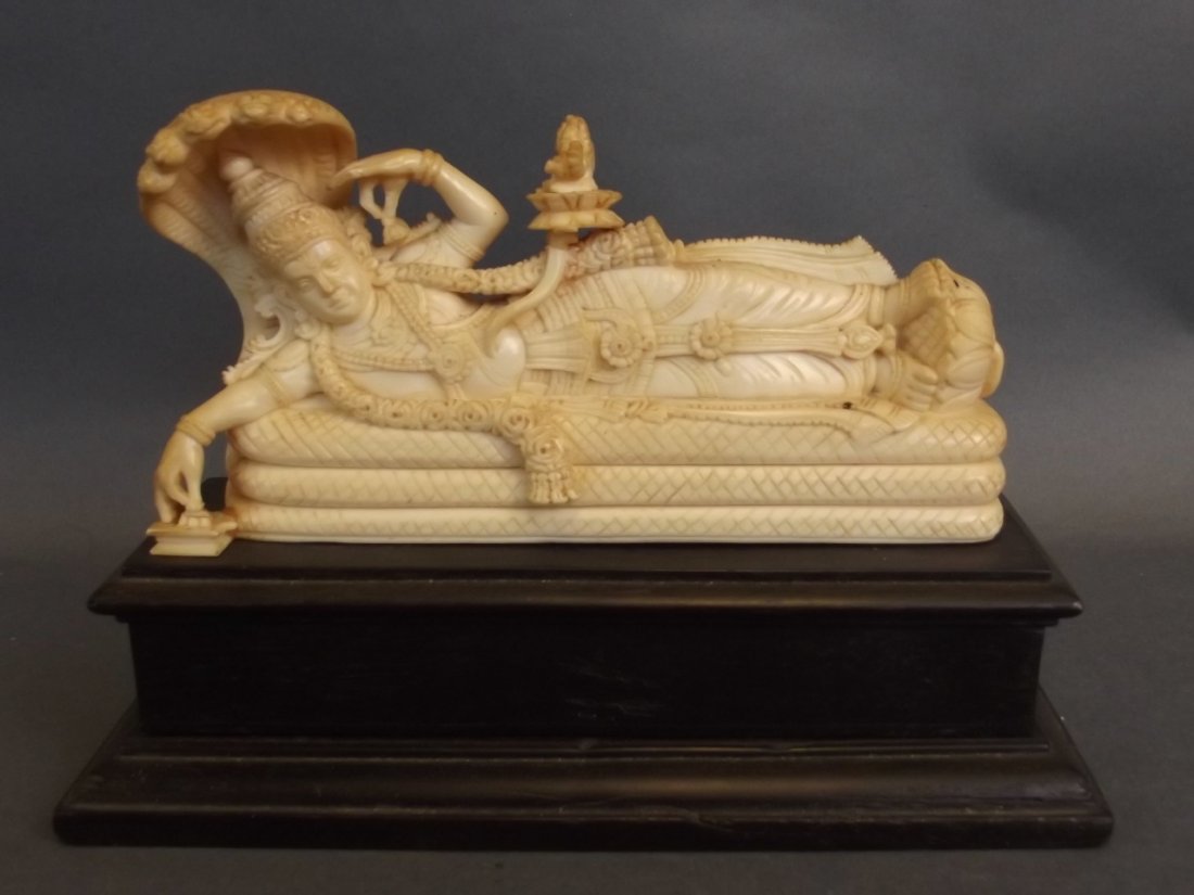 An Oriental carved ivory figure of a reclining deity on (1 of 2)