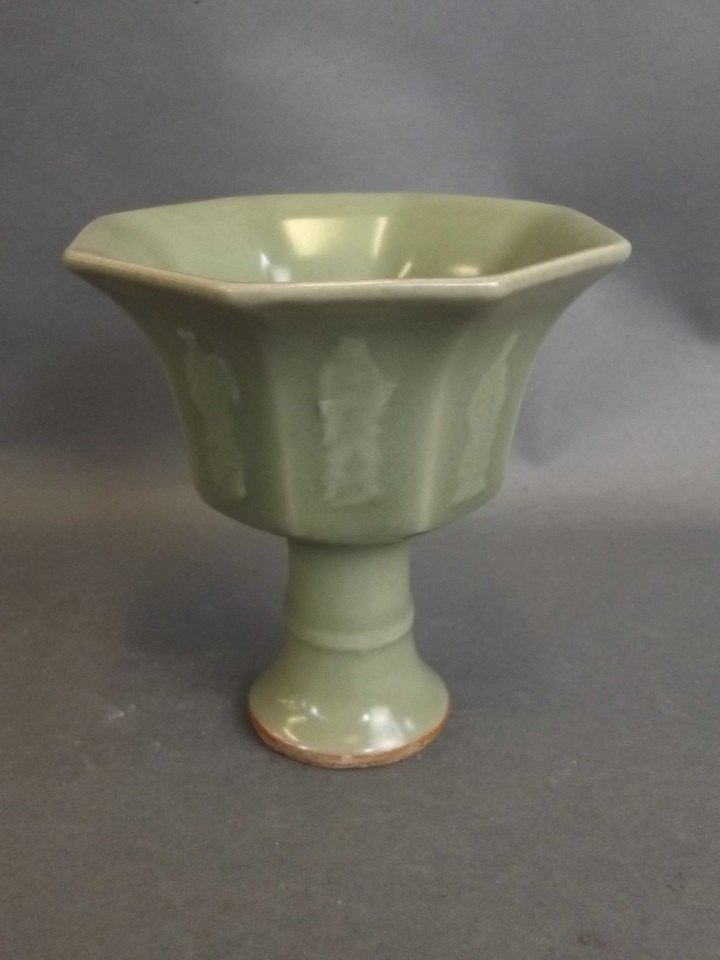 A Chinese green glazed octagonal pottery stem cup with: A Chinese green glazed octagonal pottery stem cup with relief decoration of the Eight Immortals, 4" x 4"