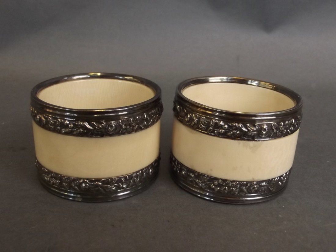 A pair of ivory and silver mounted serviette rings with: A pair of ivory and silver mounted serviette rings with repouss floral decoration, 2" diameter