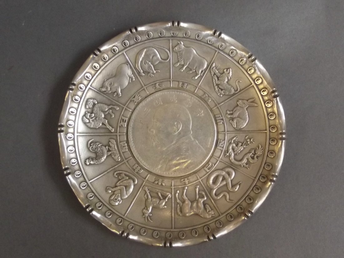 A Chinese silvered metal coin dish decorated with: A Chinese silvered metal coin dish decorated with zodiac animals, impressed 'Wai Kee 90 Silver' to base, 4" diameter