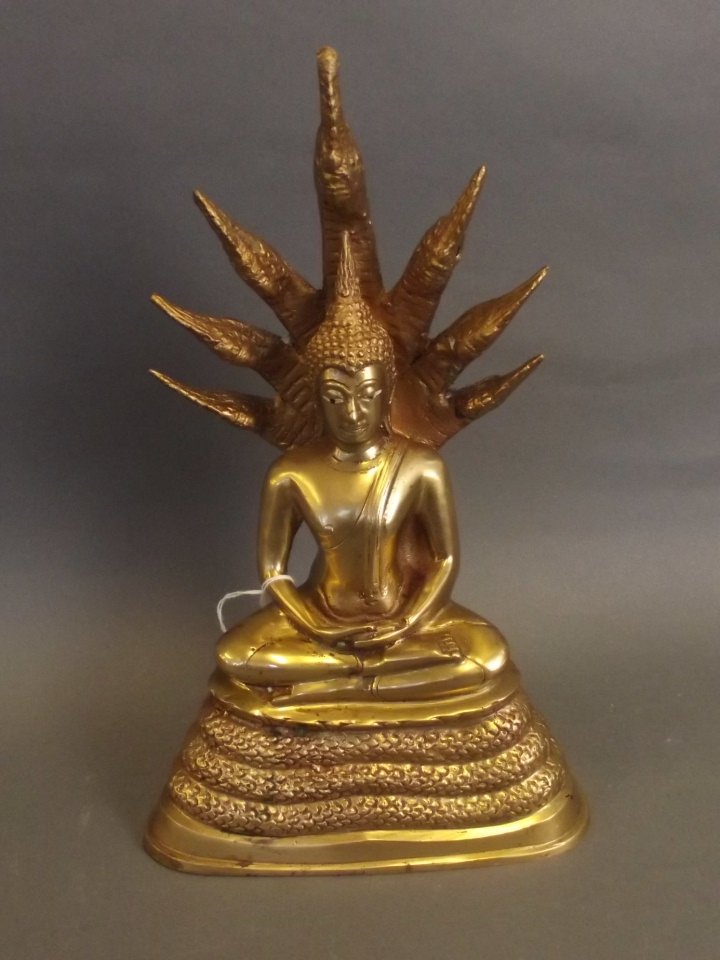 An Oriental polished brass figure of Buddha seated on a (1 of 2)