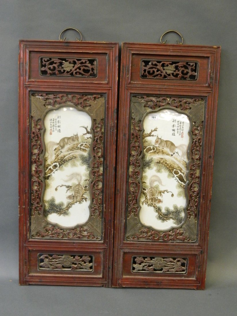 A pair of Chinese enamelled porcelain panels depicting: A pair of Chinese enamelled porcelain panels depicting squirrels on cypress trees, mounted in carved and pierced hardwood frames, 14" x 35"