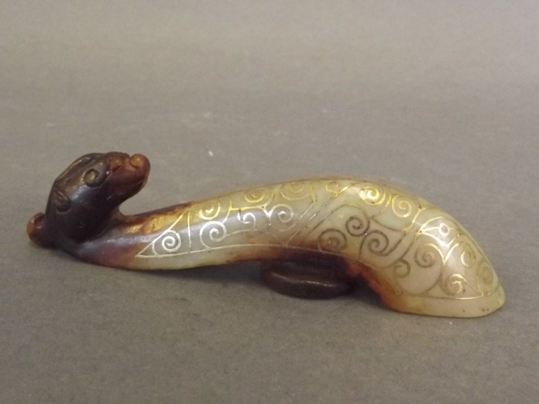 A Chinese gilt silver inlaid jade belt hook with carved: A Chinese gilt silver inlaid jade belt hook with carved dragon mask to end, 4" long
