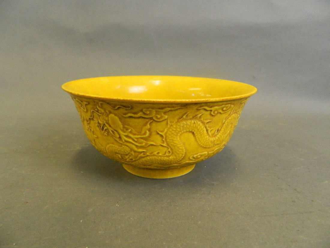 A Chinese yellow ground porcelain rice bowl with raised: A Chinese yellow ground porcelain rice bowl with raised dragon decoration, seal mark to base, 6" diameter