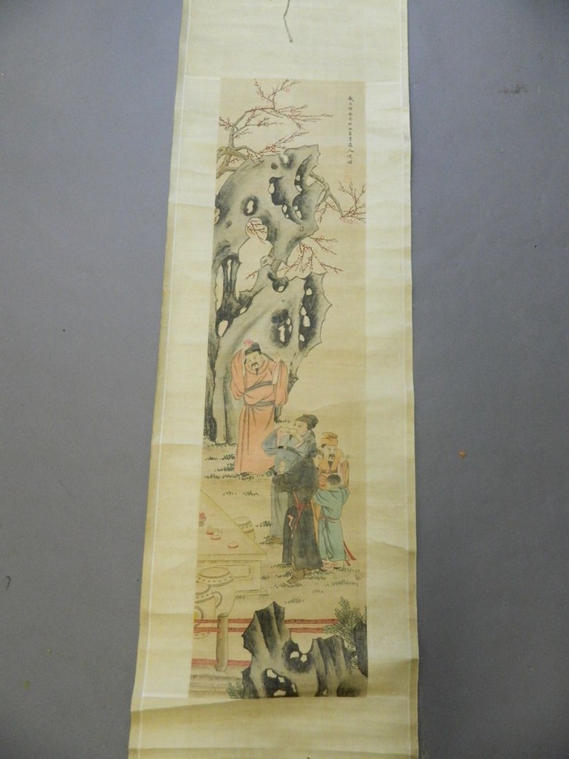 A Chinese watercolour scroll depicting figures under a: A Chinese watercolour scroll depicting figures under a prunus tree by a rocky outcrop, 12_" x 48_"