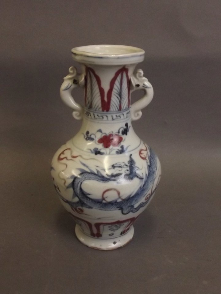 A Chinese Ming style blue and white porcelain twin: A Chinese Ming style blue and white porcelain twin handled vase decorated with a dragon chasing the flaming pearl, with red highlights, 7" high
