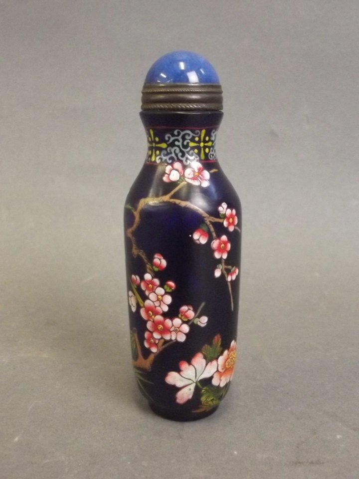 A Peking glass snuff bottle with enamelled prunus: A Peking glass snuff bottle with enamelled prunus blossom and lotus flower decoration on a blue ground, 4 character mark to base, 3_" high