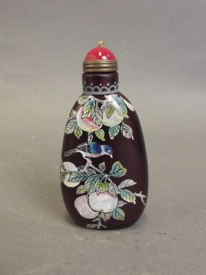 A Peking glass snuff bottle with enamelled decoration: A Peking glass snuff bottle with enamelled decoration of birds perched on peach and pear branches, 4 character mark to base, 3" high