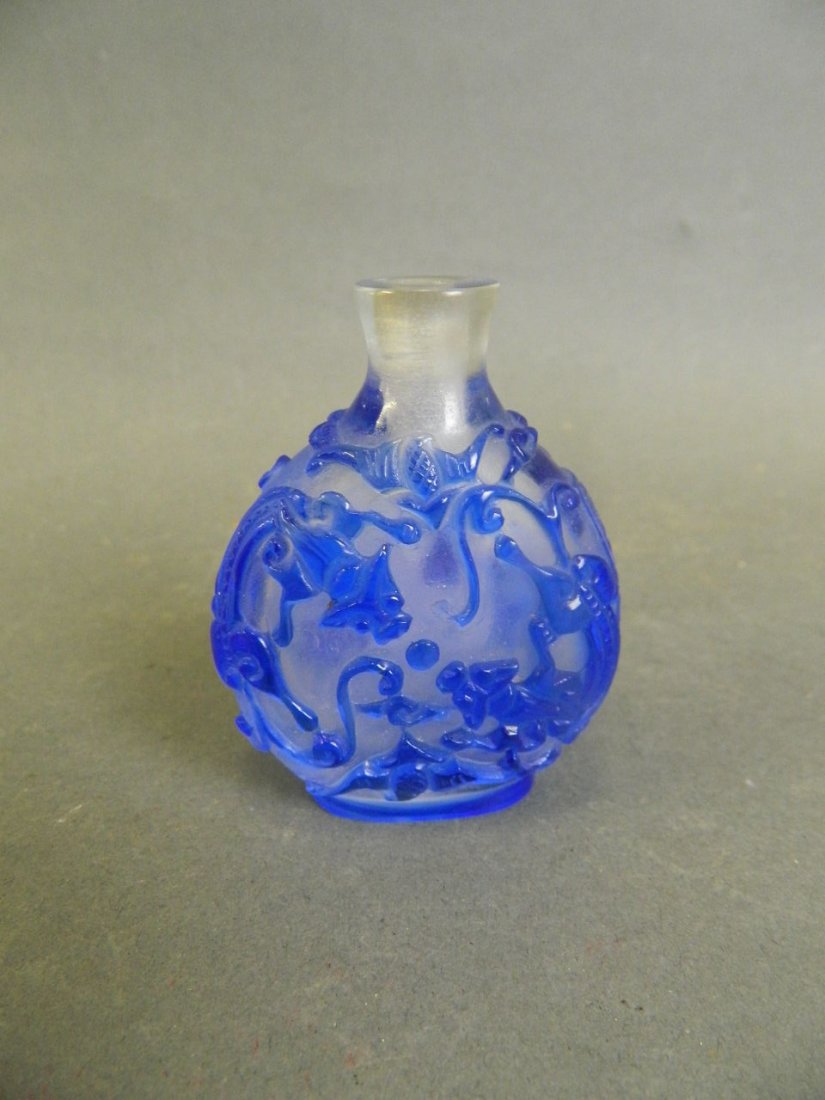 A Peking glass snuff bottle with carved and blue enamel: A Peking glass snuff bottle with carved and blue enamel kylin and bat decoration, 4 character mark to shoulder, 3" high