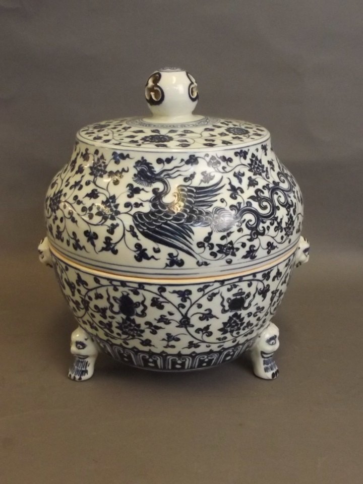 A large Chinese Ming style blue and white porcelain: A large Chinese Ming style blue and white porcelain censer with twin mask handles and painted phoenix, lotus flower and Buddhist treasure decoration, on tripod paw feet, 11" high
