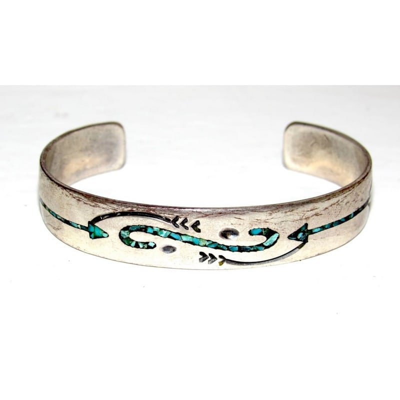 Vintage Navajo Sterling Silver Turquoise Chip Inlay Cuff Bracelet – Gibson Gene: Vintage Navajo sterling silver cuff bracelet by Gibson Gene, featuring turquoise chip inlay set within a flowing stamped arrow and scroll design. The turquoise inlay adds color and movement to the sol