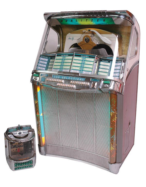 Wurlitzer Jukebox.: Model 2100 art deco style jukebox operating on 45 rpm records accompanied with the original Wurlitzer Wallbox. Size: 35" x 55". Cond.: Good to very good overall.