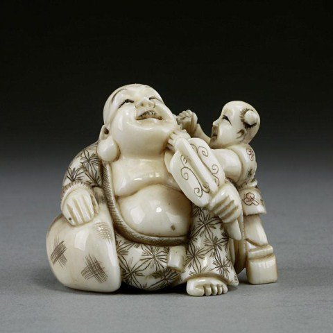 IVORY NETSUKE FIGURAL GROUP: Of a Buddha holding a fan and a child playfully tugging at his ear. Artist's signature on the base. H: 1 3/8 in.(3.5cm)