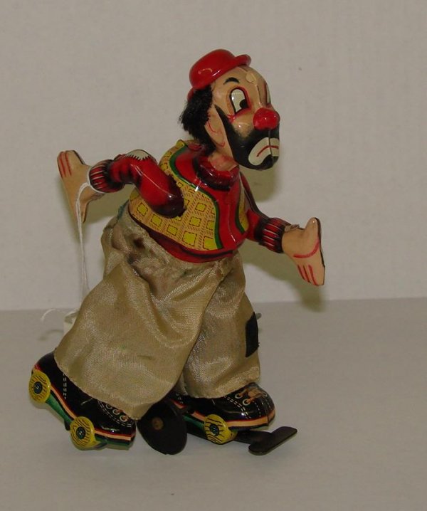 1950's TPS SKATING CLOWN: VINTAGE TIN LITHO WIND UP CLOWN ON ROLLER SKATES BY TPS, JAPAN. APPROX. 5-3/4" TALL. INNER WHEEL SHOWS WEAR.