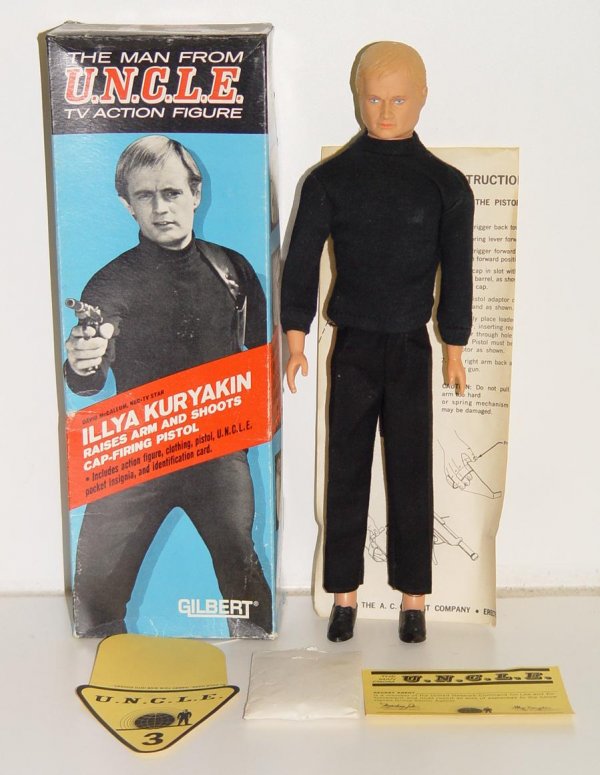 "MAN FROM U.N.C.L.E" ILLYA KURYAKIN FIGURE: 12 1/2" TALL. 1965, MADE BY THE A.C. GILBERT CO. DESIGNED WITH SPRING-LOADED ARM THAT WORKS, COMES WITH SMALL CAP-FIRING GUN STILL IN ORIG. BAG. INCLUDES U.N.C.L.E. POCKET INSIGNIA AND ID CARD. FIGURE