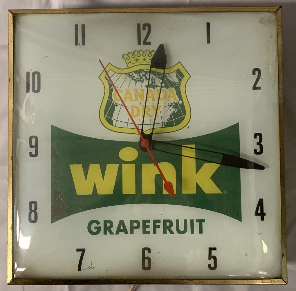 Canada Dry Wink Grapefruit Advertising Clock: Square clock with bubble glass and gold metal rim. Approx. 15-1/4" x 15-1/4". Made by Pam Clock Co, New Rochelle, NY. Some pitting to the gold metal edges and areas of crackling and paint loss on the