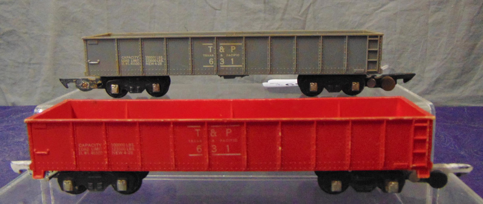 Scarce Gray & Red American Flyer 631 Gondolas: S Gauge. Includes the 1st 631 in unpainted gray plastic, missing steps; 1952 painted red variation. They show moderate playwear and would benefit from a cleaning. From the Frank Pisani Collection.