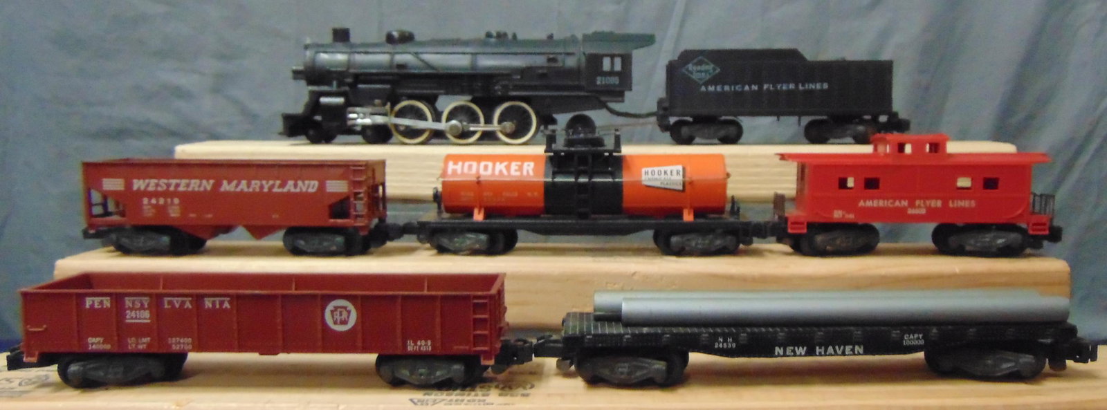6Pc American Flyer 21085 Steam Freight Set: S Gauge. Includes a 21085 Pacific steam loco & tender; 24324 Hooker tank car, 1 cracked step; 24219 WM hopper, step intact; 24106 PRR gondola; 24539 NH Pipe Car; 24603 AFL Caboose. All have K/C with i
