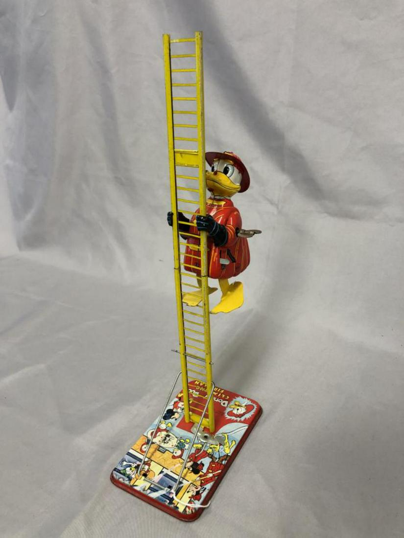 Linemar Donald Duck Climbing Fireman Toy.: Tin litho wind-up with the original ladder. Marked "Walt Disney Productions". Some minor scratching and wear on arms and outside of ladder. 14 1/2" tall. Working Condition when tested.
