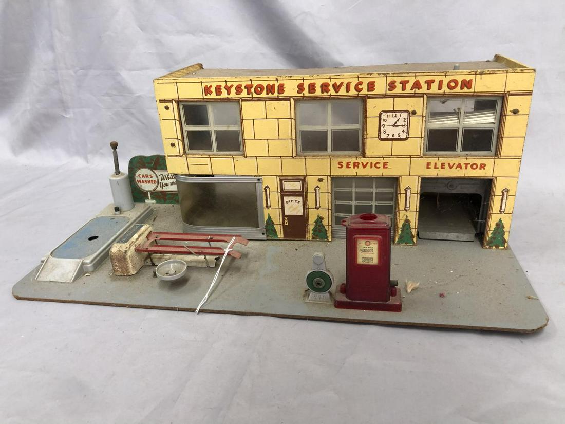 Keystone Service Station: Paper litho on masonite with plastic accessories 13 X 19”. Includes a car wash, oil change lift with oil pan; Gas Pump, incomplete, air pump. Garage lift has a partial door, needs stringing and unit