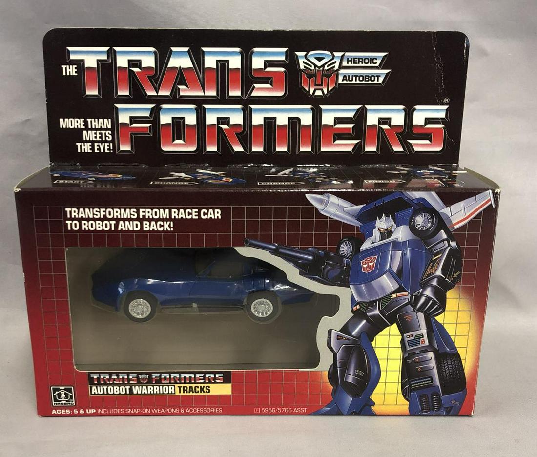 1985 MIB Transformers G1 "Tracks" Autobot Complete: Hasbro. Mint in opened box and complete. Box is opened on at the right edge, where the accessories are housed. Left side of box is still factory taped. Figure has never been removed from box. Complete