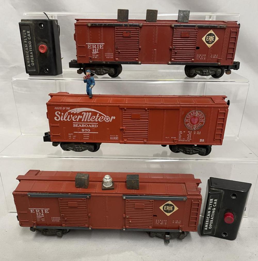 American Flyer 957, 970 & 974 Operating Cars: S Gauge. Includes a 957 Eire Operating boxcar with button and 3pc load, intact brake-wheel, oxidation on chassis; 970 SilverMeteor Walking brakeman Car, intact brake-wheel; 974 Erie unloading car with