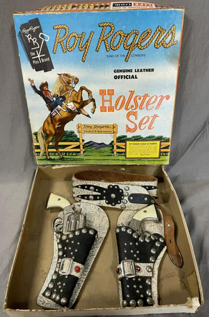 1955 Boxed Roy Rogers Cap Pistol Set: Includes a pair of Kilgore Peace Maker cast iron cap pistols, both working with ornate leather double holster with all plastic bullets in harness. It shows light play wear with lightly worn outfit box