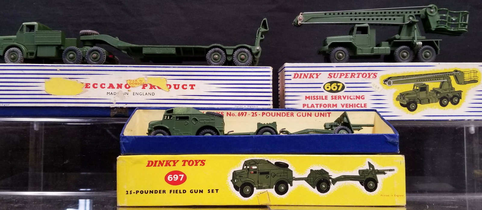 Lot of Three Dinky Military Vehicles Boxed: Includes #660 Tank Transporter, #697 25 Pounder Filed Gun Set (Vehicle Roof Has Stain) & #667 Missile Servicing Platform Vehicle. Boxes show wear and some flaps are torn and or missing.