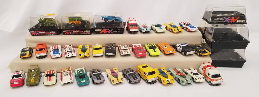 (34) Aurora AFX Slot Cars and 8 Cases: 34 Aurora AFX slot cars with 8 hard plastic cases; various models. Some wear to some of the cars.