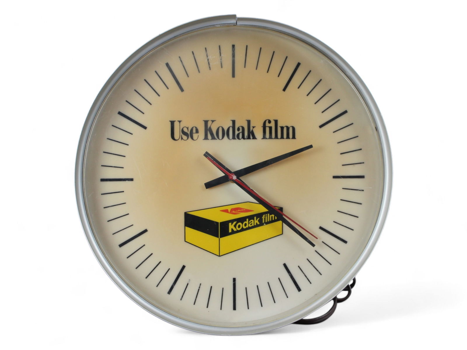 Kodak Film Lighted Advertising Clock: A lighted clock advertising Kodak film with the clock face marked "Use Kodak film" and a picture of a box of Kodak film. Clock has hour, minute, and second hands. Measures 16" in diameter x 5.25"D.