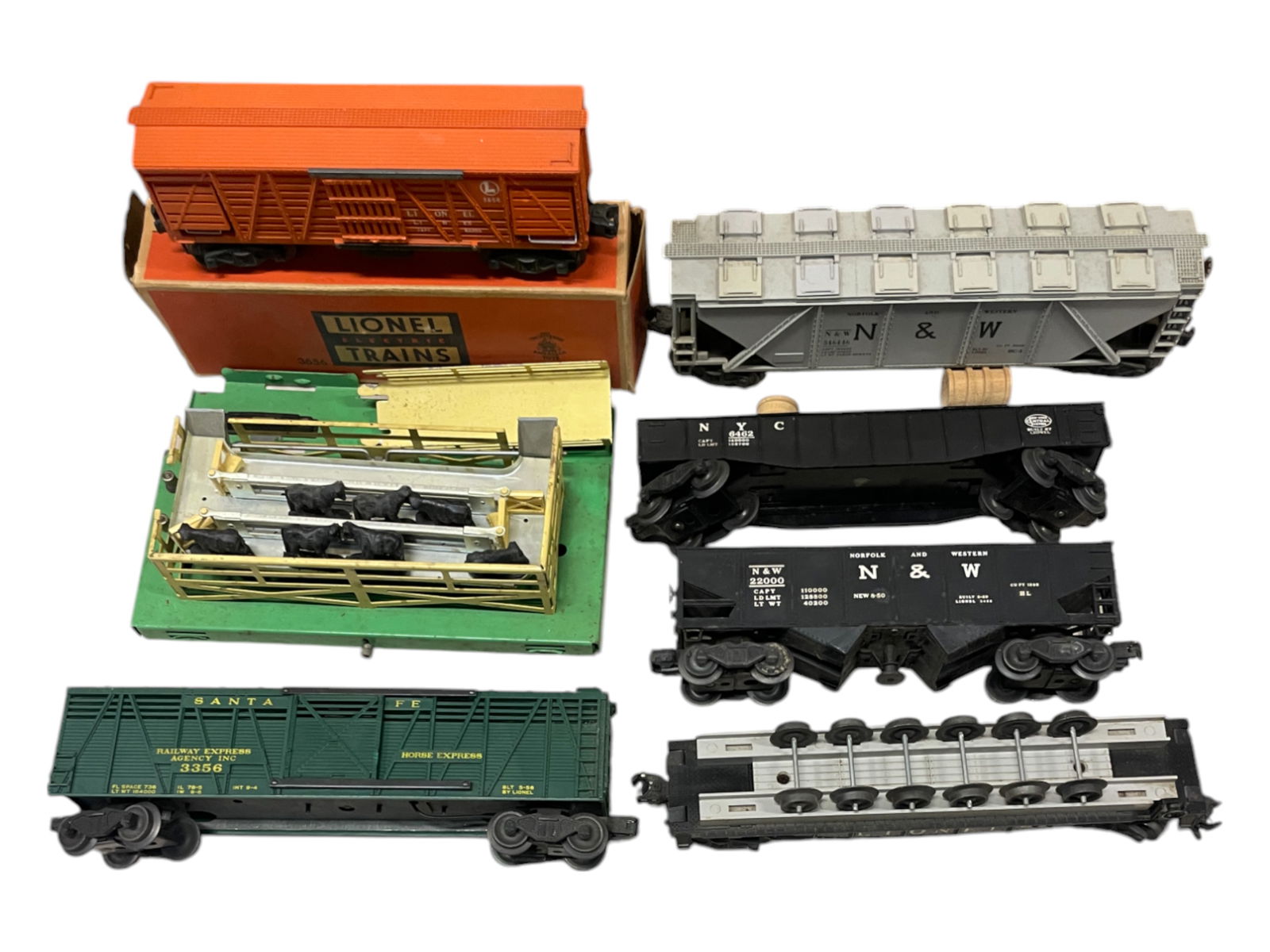 6 Lionel Freight Cars: Includes a 3656 Cattle Car set with car ob only; 6446 Cement car; 6462 Gondola with drums; 3456 N&W oper Hopper; 6262 Wheel car with correct unrun load; 3356 Oper Horse Car, only. All show light to mo